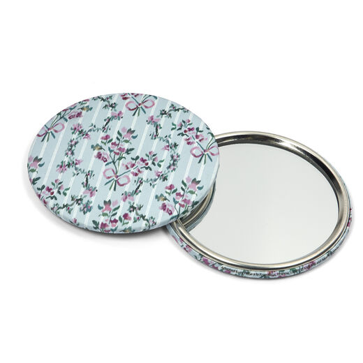 Two round pocket mirrors. One is arranged to show the mirrored side, while the other one displays the floral pattern on pale blue on the other side.
